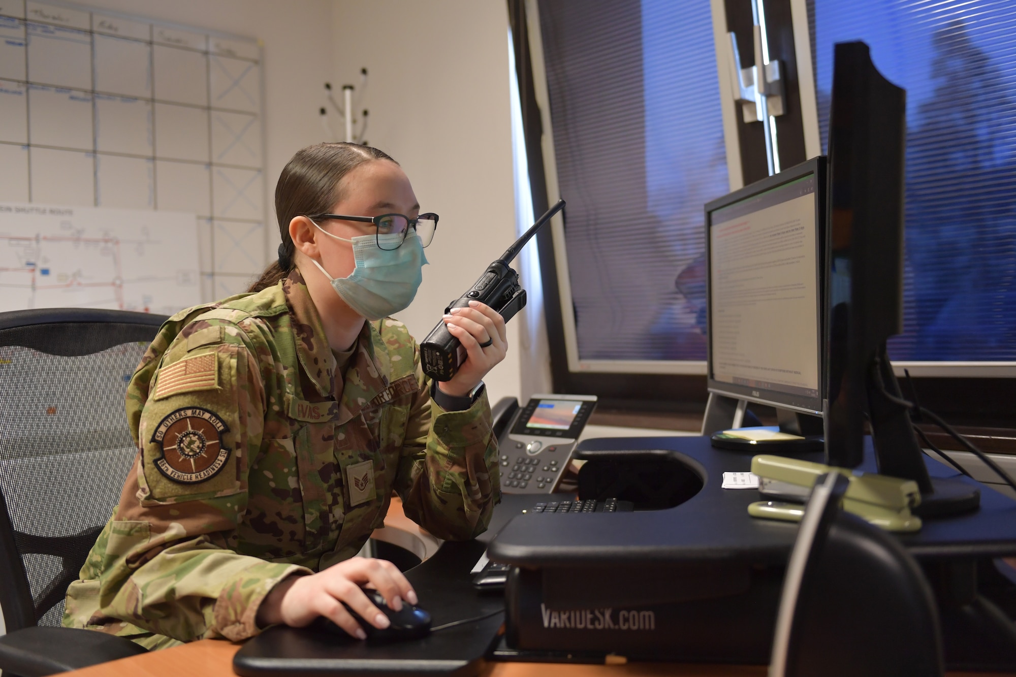 Airman sitting at a desk, holding a radio.