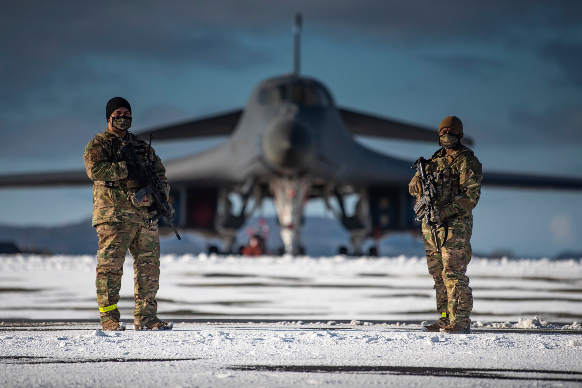 Two defenders assigned to the 7th Security Forces Squadron guard a B-1B Lancer on the flightline at Ørland Air Force Station, Norway, March 7, 2021. Eight defenders deployed with the 9th Expeditionary Bomb Squadron to support Bomber Task Force Europe as an Internal Security Response Team to guard war-fighting assets. (U.S. Air Force photo by Airman 1st Class Colin Hollowell)