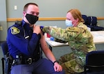 A Michigan Army National Guard medic gives a final dose of the COVID-19 vaccine to a Michigan State Police trooper at police headquarters in Dimondale, Michigan, March 4, 2021. The Michigan National Guard is helping the Michigan Department of Health and Human Services support local health care organizations in administering the vaccine to Michiganders.