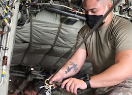 Army Spc. Christian Ramos, 151th Quartermaster Detachment, Fort Bragg, North Carolina, serves as team leader for the air drop system, equipment and repair section. Once pallets are loaded on the aircraft, Ramos and the other riggers use strings and rubber bands to attach parachutes to static lines on both the left and right sides of the aircraft.