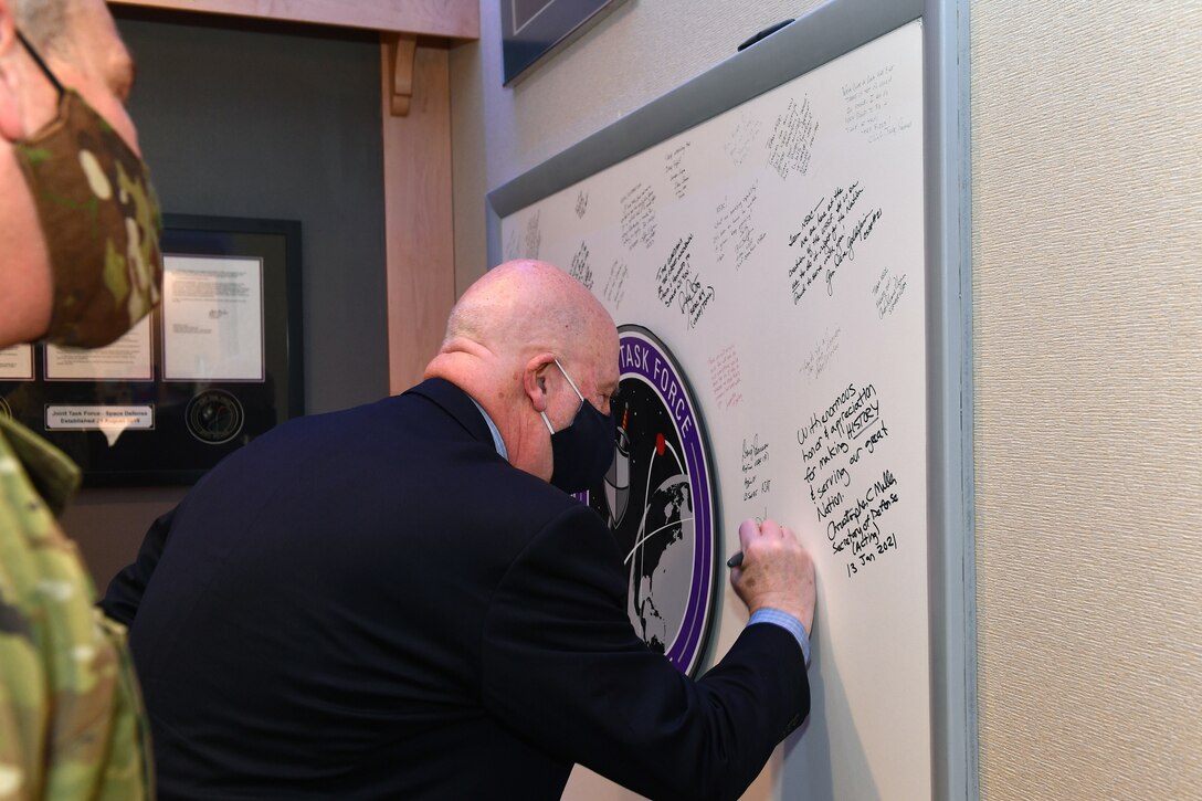 Senior Air Force civilian writes message on organization's board commemorating his visit.
