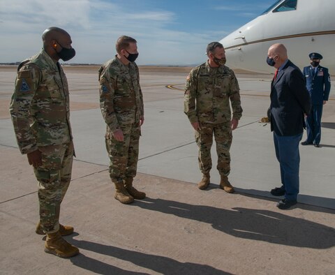 Four men on the Peterson Air Force Base flight line. Three senior leaders greeting the Acting Secretary of the Air Force.