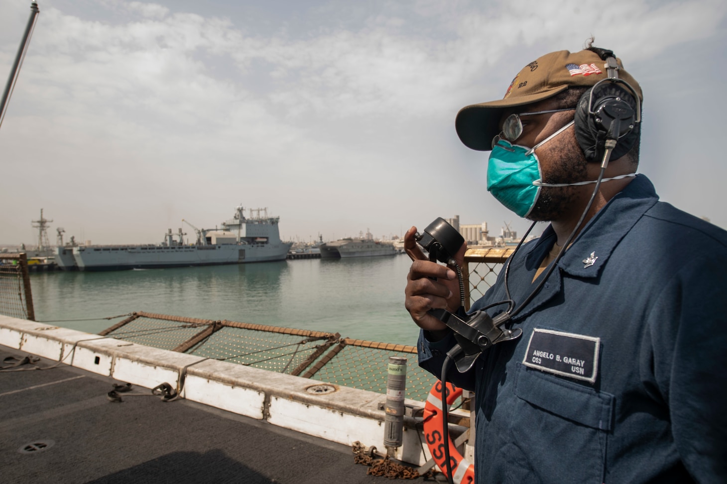 Operations Specialist 2nd Class Angelo Garay stands watch on the flight deck of amphibious transport dock ship USS San Diego (LPD 22) as the ship departs Manama, Bahrain.
