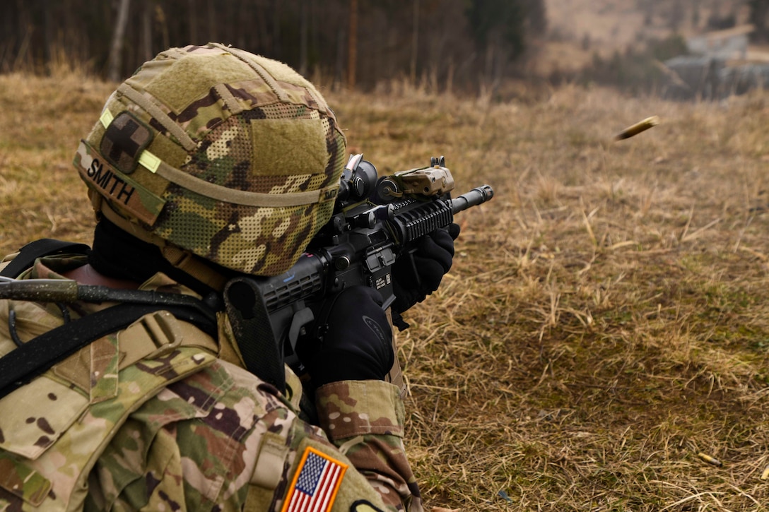 A soldier fires a weapon in a forest.
