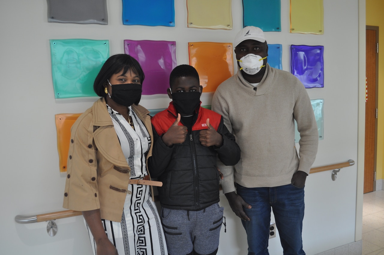 A family wearing personal protective equipment poses for a photo inside a hospital.