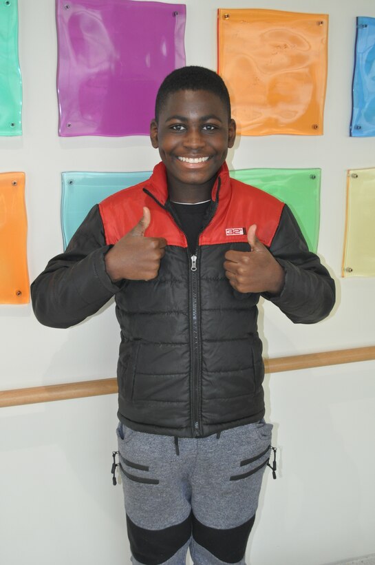 A young boy poses for a photo inside a hospital.