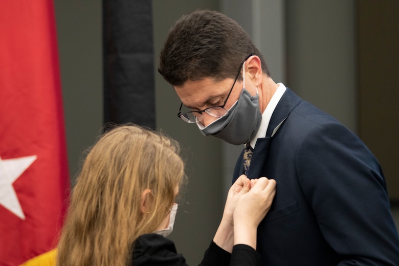 Emma Russo pins father, Dr. Edmond Russo, director of the U.S. Army Engineer Research and Development Center’s (ERDC) Environmental Laboratory (EL), with the Senior Executive Service (SES) pin during a hybrid virtual and in-person SES induction ceremony held at the ERDC-EL building in Vicksburg, Miss., March 11, 2021.