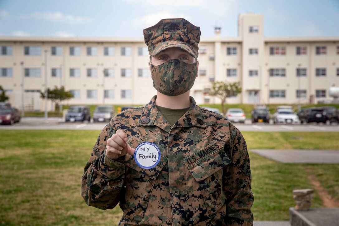 U.S. Marine Corps Staff Sgt. Felicia White, a supply chief with Camp Kinser Post Office, shows that her family is the reason she received her second dose of the COVID-19 vaccine at the U.S. Naval Hospital Okinawa, on Camp Foster, Mar. 2, 2021. On Jan. 11, 2021, active duty personnel were permitted to receive the vaccine. As service members receive the second dose of the vaccine, they are given a sticker stating ‘I got my COVID-19 vaccine because…’ This personal memento signifies their own unique reason to receive the vaccine. White is a native to El Paso, Texas. (U.S. Marine Corps photo by Lance Cpl. Zachary Larsen)