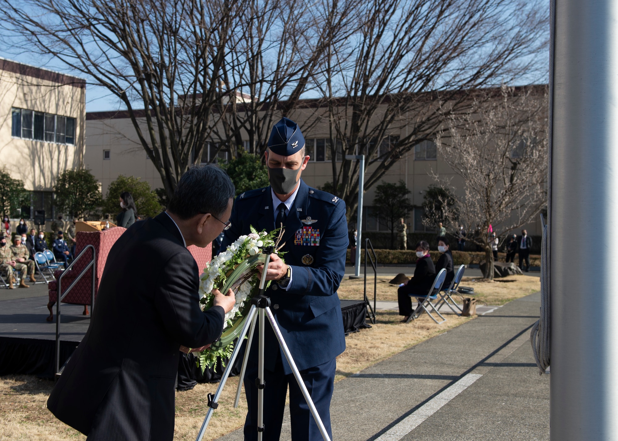 Col. Andrew Campbell, 374th Airlift Wing commander, and Takahisa Matsuda, North Kanto Defense Bureau director general place a wreath at the base of a Japanese flagpole during a ceremony for the 10th Anniversary of the Great East Japan Earthquake and the Operation Tomodachi support efforts at Yokota Air Base, Japan, March 11, 2021. The wreath represents the loss of nearly 16,000 lives during the earthquake, and the tsunami that followed. (U.S. Air Force photo by Staff Sgt. Joshua Edwards)