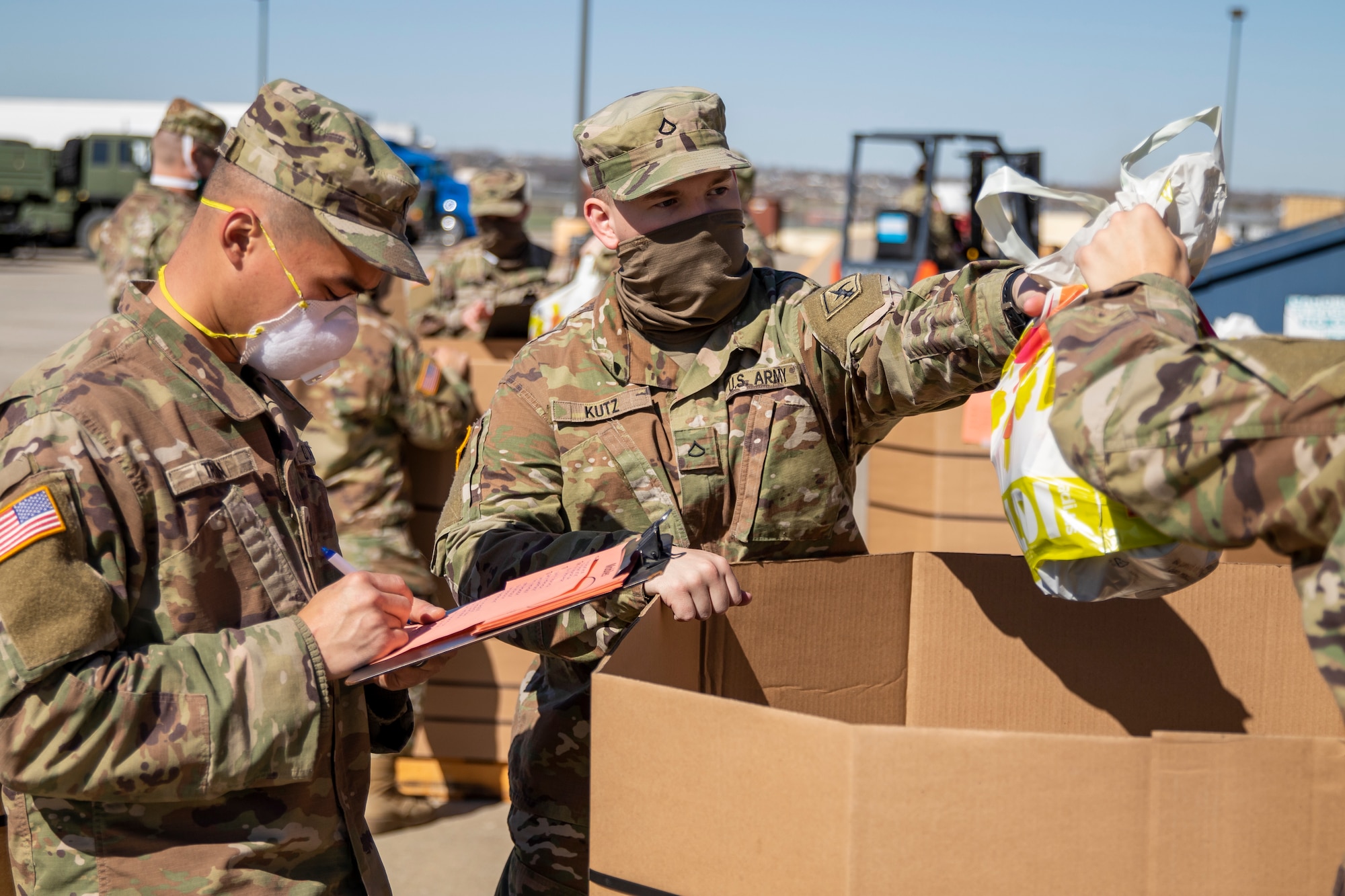 Nebraska Army National Guard Pfc. Nicholas Kutz, 267th Maintenance Company, center, helps pack bags of mostly nonperishable items, April 21, 2020, at the National Guard warehouse in Lincoln, to be distributed to those in need in Southeast Nebraska through the Food Bank of Lincoln. The Nebraska National Guard has supported multiple food bank operations throughout the state during the COVID-19 pandemic.