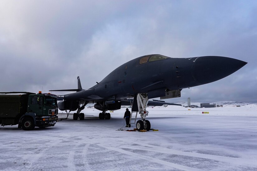 A jet gets refueled on a snowy tarmac.