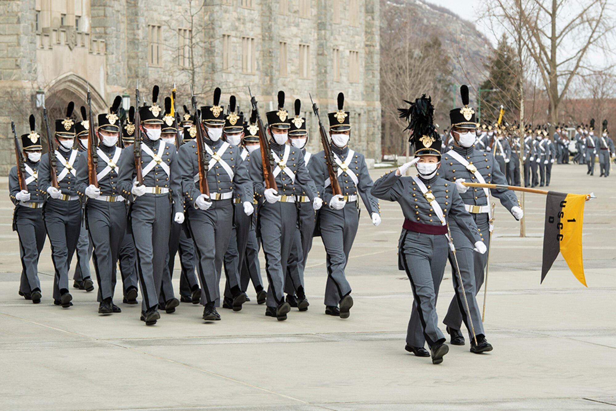U.S. Military Academy cadets march in formation in front of a building.