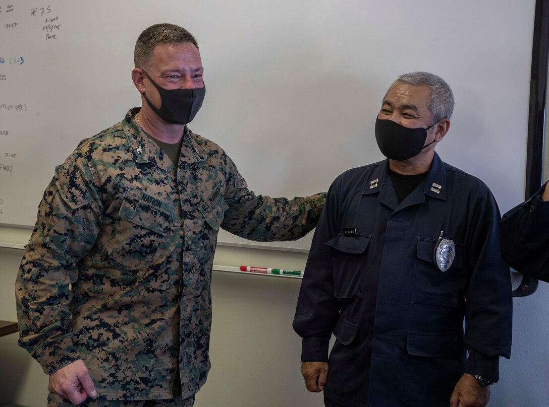 U.S. Marine Corps Col. Matthew Nation, the commanding officer of Headquarters Battalion, 3d Marine Division, laughs with Japanese Security Guard (JSG) Capt. Akira Miyagi on Camp Courtney, Okinawa, Japan, March 10, 2021. JSG was presented with challenge coins to highlight their efforts after protecting the installation by stopping an unauthorized intruding vehicle. (U.S. Marine Corps photo by Lance Cpl. Zachary Larsen)
