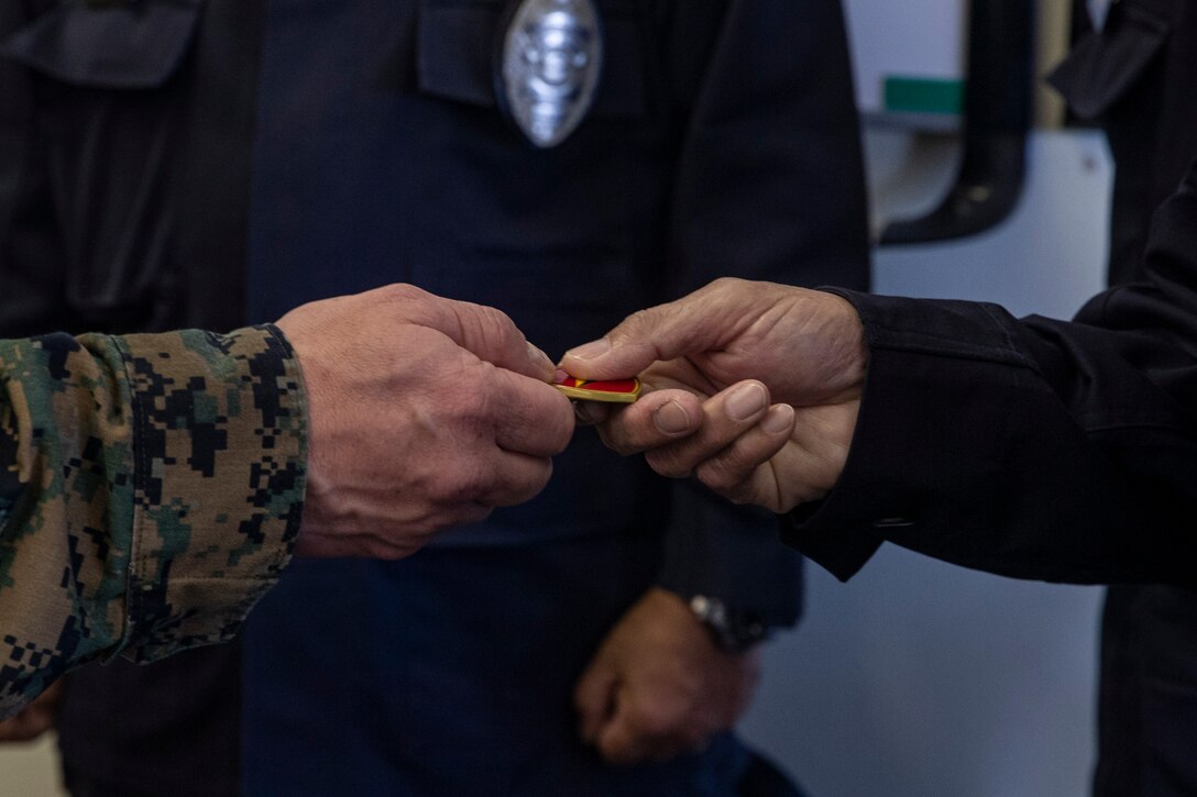 U.S. Marine Corps Col. Matthew Nation, the commanding officer Headquarters Battalion, 3d Marine Division, awards Japanese Security Guards (JSG) with challenge coins on Camp Courtney, Okinawa, Japan, March 10, 2021. JSG was presented with challenge coins to highlight their efforts after protecting the installation by stopping an unauthorized intruding vehicle. (U.S. Marine Corps photo by Lance Cpl. Zachary Larsen)