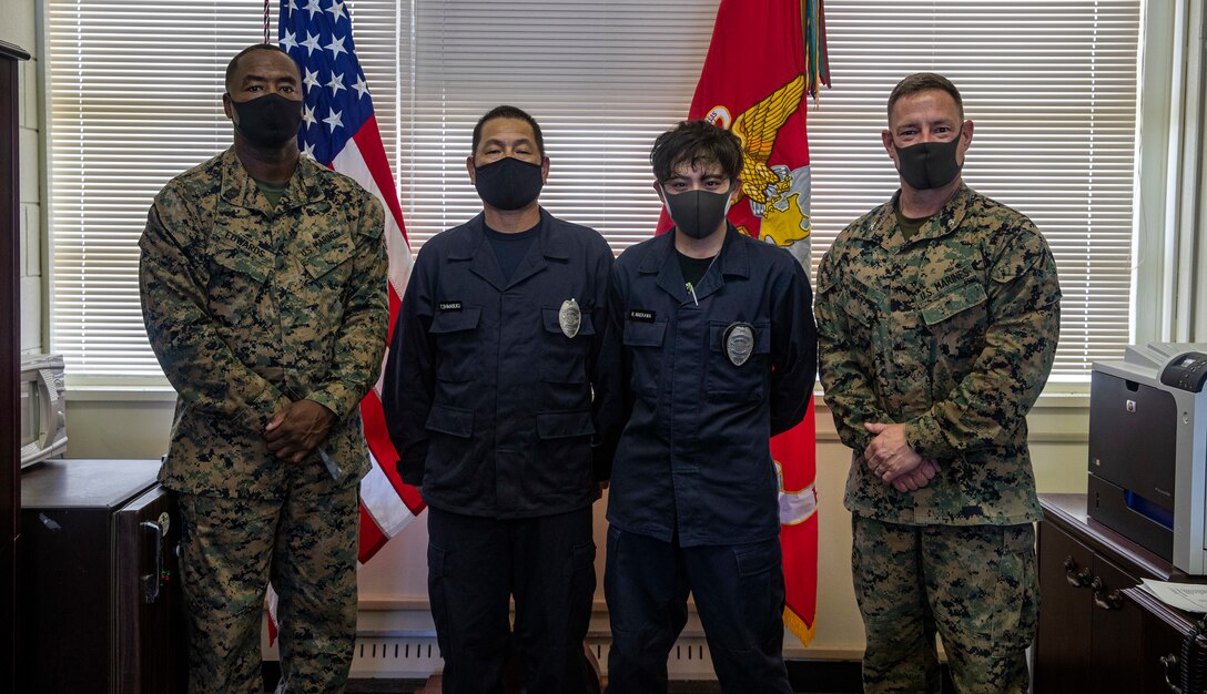 U.S. Marine Corps Sgt. Maj. Auburn Edwards II, the sergeant major of Headquarters (HQ) Battalion, 3d Marine Division (3d MarDiv), left, Japanese Security Guard (JSG) BWT3-1 Tetsuji Shimabuku, BWT3-1 Ryutaro Maekawa, and Col. Matthew Nation, the commanding officer of HQ Battalion 3d MarDiv, right, pose for a group photo on Camp Courtney, Okinawa, Japan, March 10, 2021. JSG was presented with challenge coins to highlight their efforts after protecting the installation by stopping an unauthorized intruding vehicle. (U.S. Marine Corps photo by Lance Cpl. Zachary Larsen)