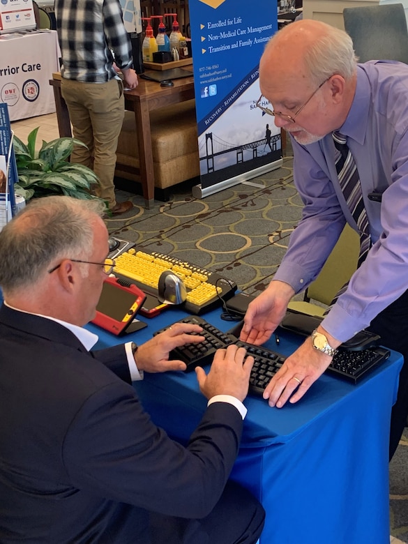 A man shows another man how to work a special keyboard.