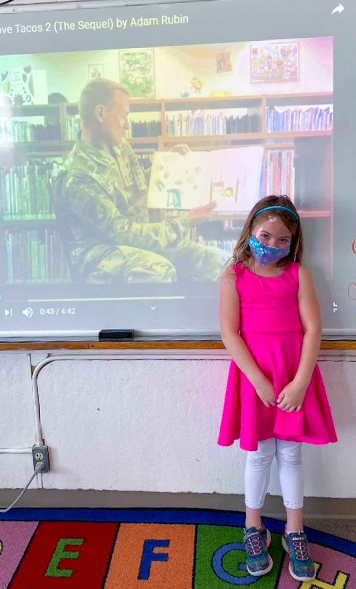 Savannah Preston, a Holloman Elementary School student, poses in front of a video of her father, Col. Thomas Preston, 49th Maintenance Group commander, reading for Read Across America March 10, 2021, on Holloman Air Force Base. Leaders of the community volunteered to read books to the students to help celebrate Read Across America. (Courtesy photo)