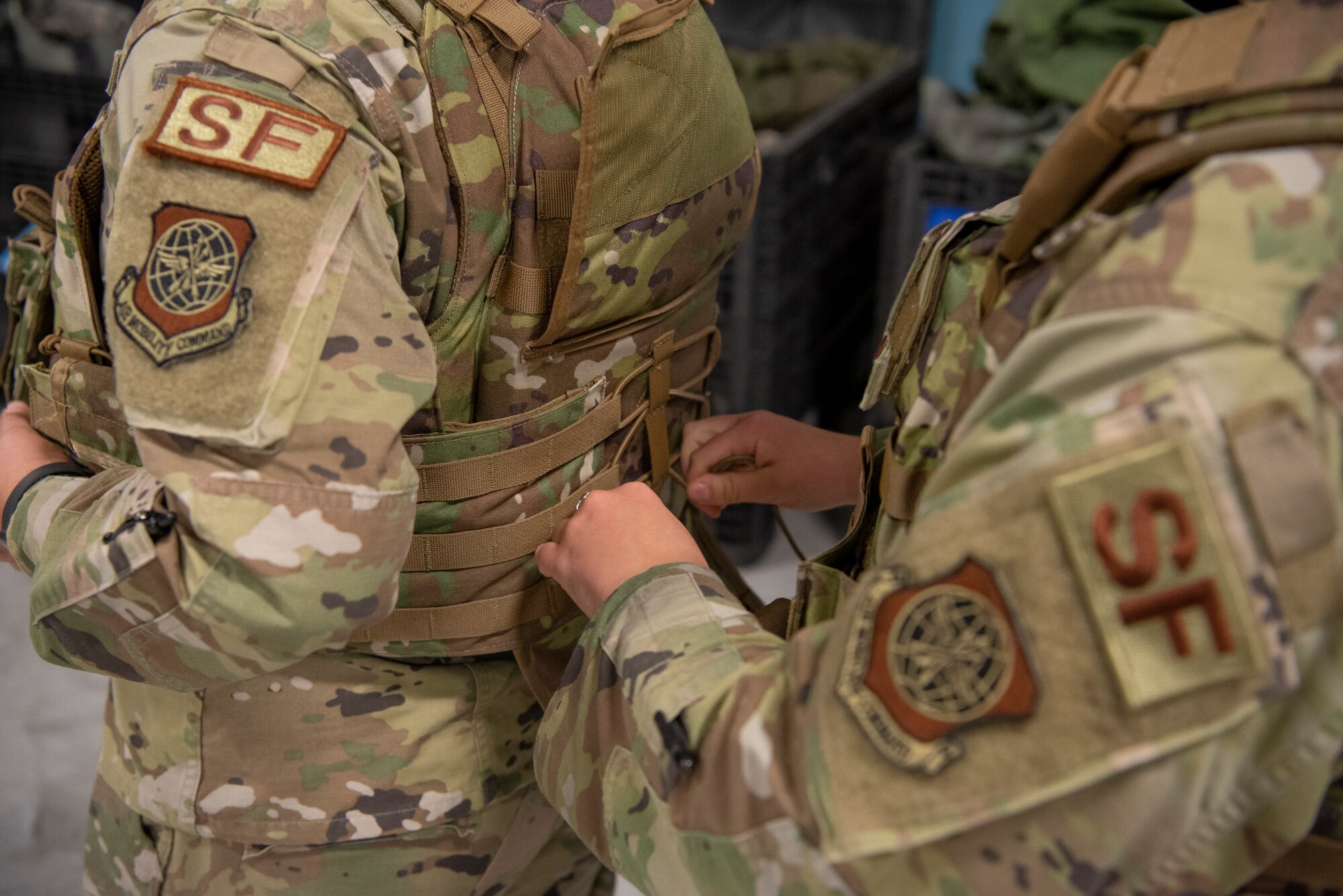 U.S. Air Force Senior Airman Adrienne Quesada, 6th Security Forces Squadron installation patrolman (right), tightens the new female Improved Outer Tactical Vest for her coworker, at MacDill Air Force Base, Fla., Feb. 17, 2021. The new body armor is designed to enhance equipment performance for women with job-specific gear requirements. It offers an adjustable corset in the back, a shorter cut for torso and shoulders that allow female defenders to be efficiently equipped to defeat any threat to MacDill.