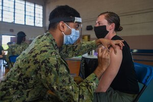 Hospital Corpsman 1st Class Sujit Rajendran, dental leading petty officer for Pre-Commissioning (PCU) John F. Kennedy (CVN 79), administers a Pfizer COVID-19 vaccine to Lt. j.g. Kelly Evertson, pilot for Helicopter Sea Combat (HSC) Squadron 11.