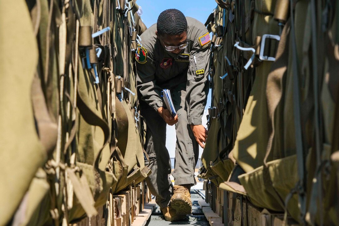An airmen walks between two rows of large parcels.