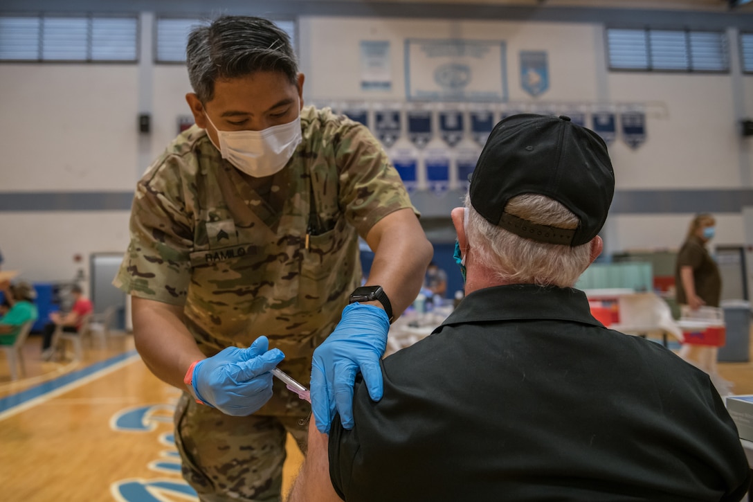 A soldier vaccinates a man.