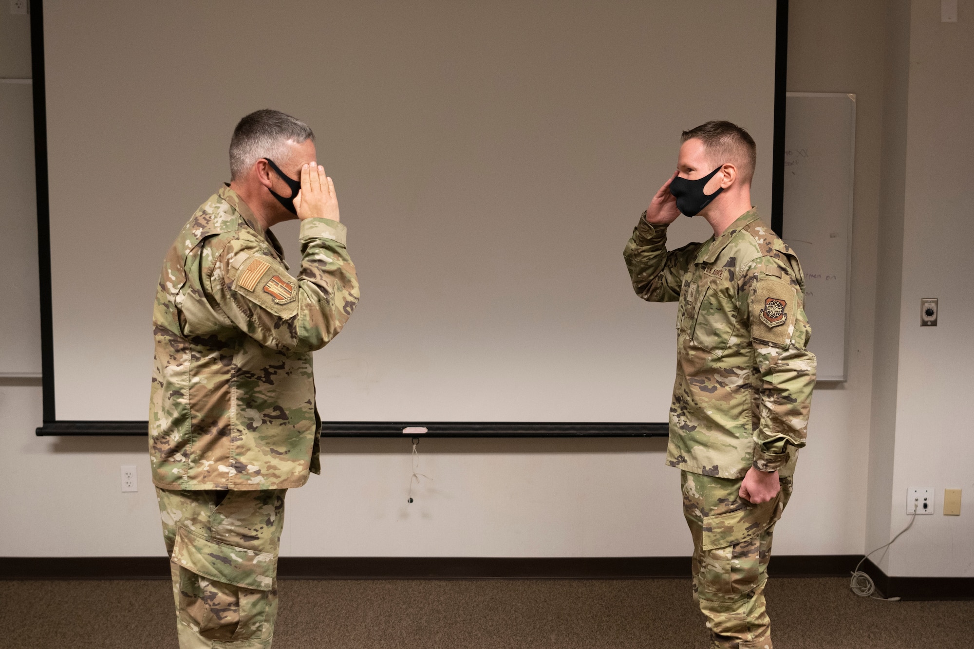 U.S. Air Force Master Sgt. Shawn Dougherty, right, 60th Aircraft Maintenance Squadron aerospace ground equipment flight chief, salutes Col. Corey Simmons, 60th Air Mobility Wing commander, during Leadership Rounds at Travis Air Force Base, California, March 12, 2021. Dougherty was coined for participating in interviews discussing the new suicide and prevention virtual reality training. Six additional individuals were also recognized for their participation in showcasing Team Travis’ new suicide and prevention, virtual reality training. (U.S. Air Force photo by Airman 1st Class Alexander Merchak)