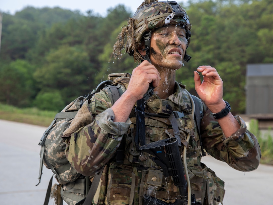 A soldier dumps water over his head to cool down.