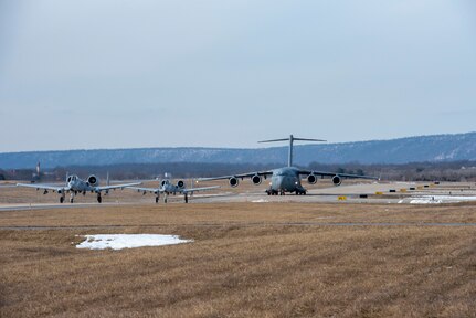 Two A-10 Thunderbolt II aircraft from the 104th Fighter Squadron of the 175th Wing, Maryland Air National Guard, and a C-17 Globemaster III with the 167th Airlift Squadron, 167th Airlift IWng, West Virginia Air National Guard, taxi to the runway at Shepherd Field, Martinsburg, West Virginia, Feb. 17, 2021, as part of an exercise to demonstrate Agile Combat Employment (ACE) capabilities.