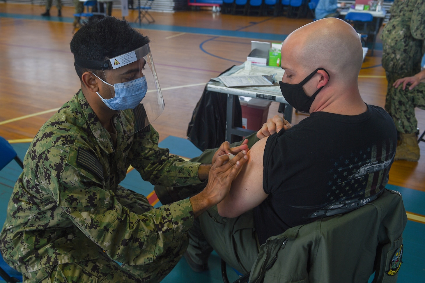 Hospital Corpsman 1st Class Sujit Rajendran, dental leading petty officer for Pre-Commissioning Unit (PCU) John F. Kennedy (CVN 79), administers a Pfizer COVID-19 vaccine to Lt. Matthew Hinkson, pilot for Helicopter Sea Combat (HSC) Squadron 11.