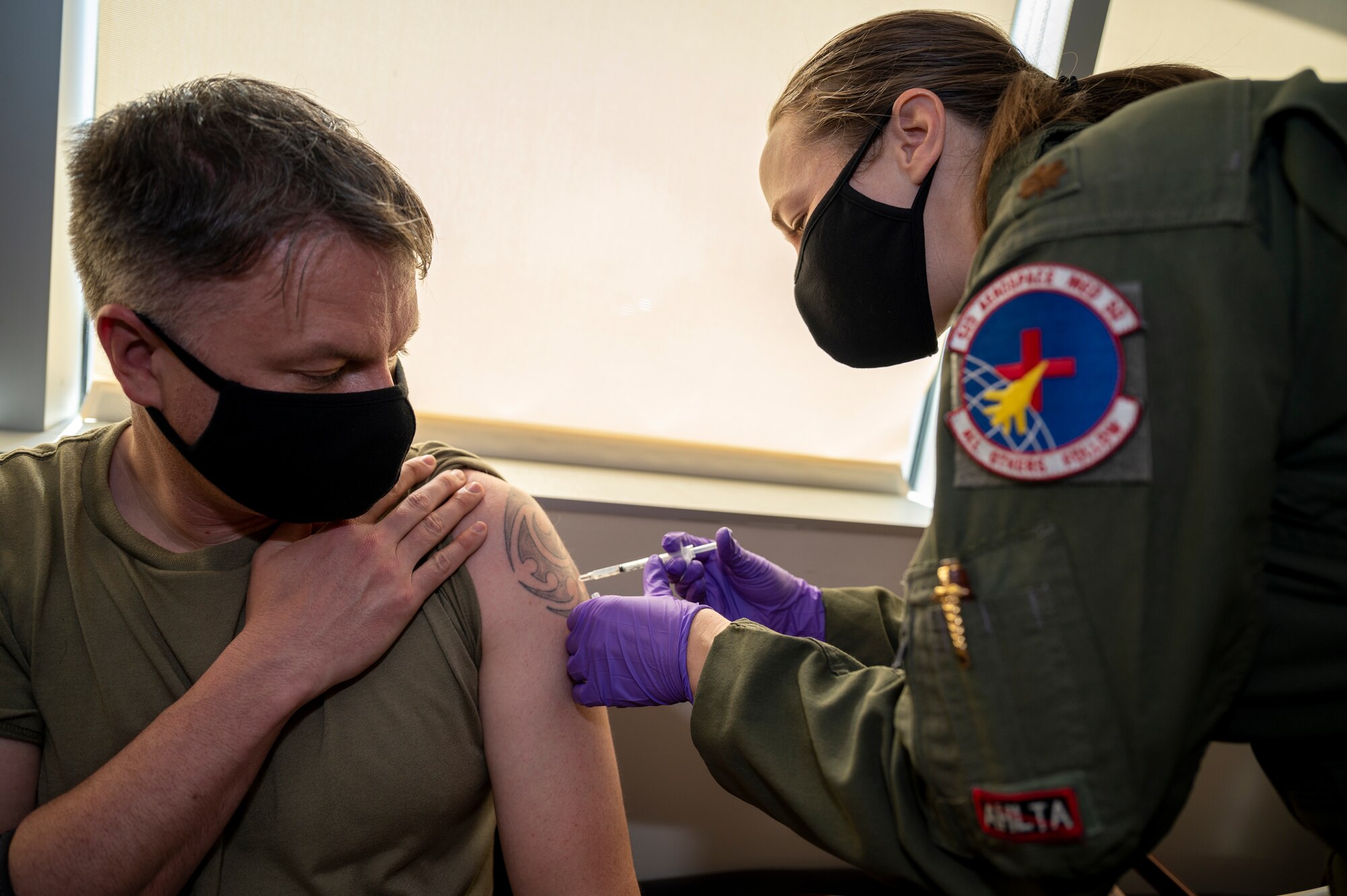 A woman administers COVID-10 vaccine into man with medical syringe.