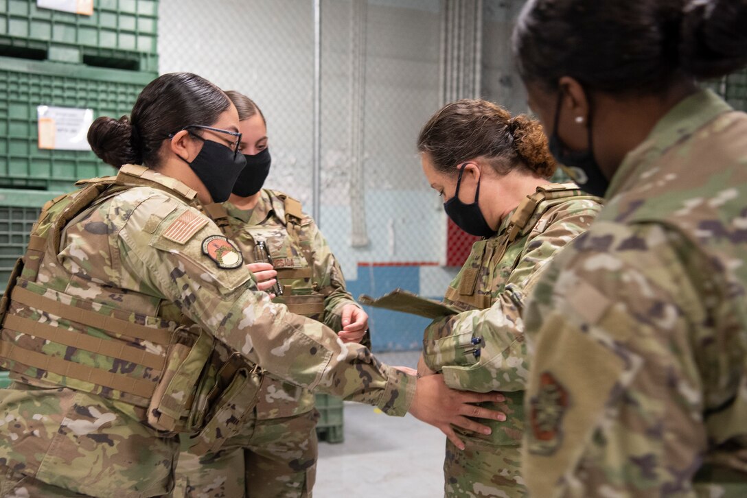 6th Security Forces Squadron Airmen (left), assist the 6th Air Refueling Wing command chief, Chief Master Sgt. Shae Gee (center), with trying on the new female Improved Outer Tactical Vest at MacDill Air Force Base, Fla., Feb. 17, 2021. The new body armor has been designed to enhance equipment performance for women with job-specific gear requirements. It offers an adjustable  corset in the back, a shorter cut for torso and shoulders that allow female defenders to be efficiently equipped to defeat any threat to MacDill.
