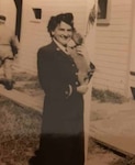 Unit 21 commanding officer Ensign Vera Hamerschlag holds her puppy outside of the LORAN station she was in charge of in 1944. U.S. Coast Guard photo.