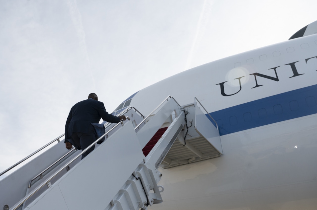 Secretary of Defense Lloyd J. Austin III walks up the stairs of an aircraft.