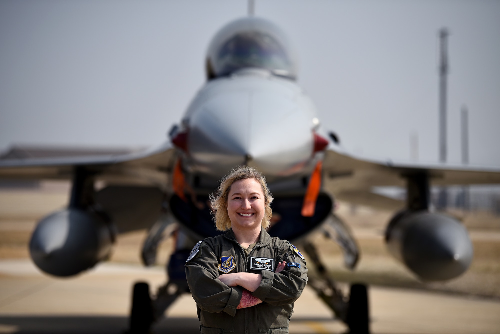 First Lt. “Grizzly” Akers, 35th Fighter Squadron F-16 Fighting Falcon pilot, poses for a photo on the flightline at Kunsan Air Base, Republic of Korea, March 8, 2021. Akers studied behavioral science at the Air Force Academy and then discovered her love for flying through their powered flight program. (U.S. Air Force photo by Senior Airman Suzie Plotnikov)
