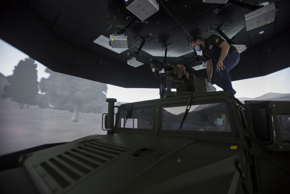 A Simulator Integration Center and Range Control Operations Complex employee helps set up a convoy simulator for Israeli Defense Forces leaders during a tour from II Marine Expeditionary Force personnel which showcased various simulation and training facilities on Camp Lejeune, N.C., Mar. 10, 2021.