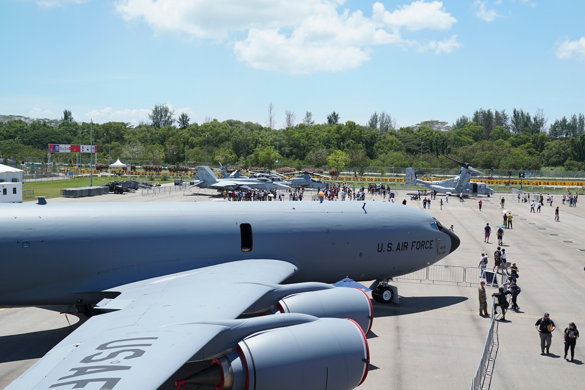 People walk on a tarmac looking at large planes.