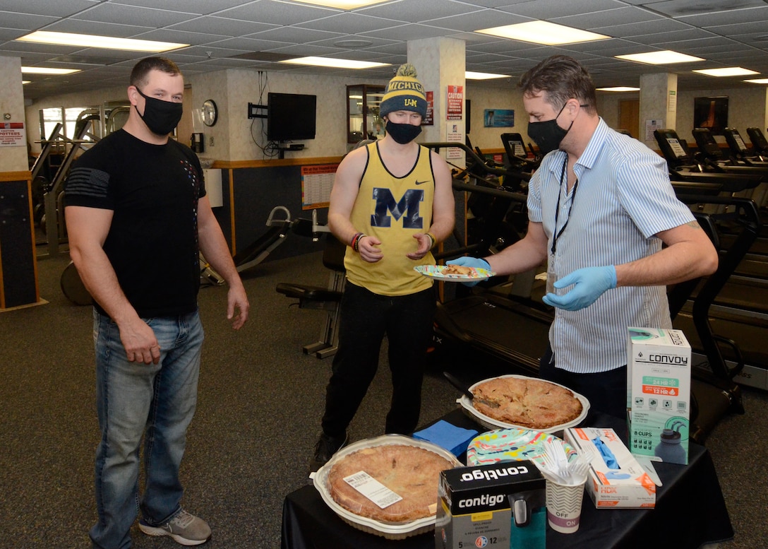 David Potter, left, and Schuyler Slone, center, receive their slices of pie from Dan Roberts, a recreation assistant and personal trainer with MWR in the Fitness Center March 12 during the first day of the annual Pi Day event.