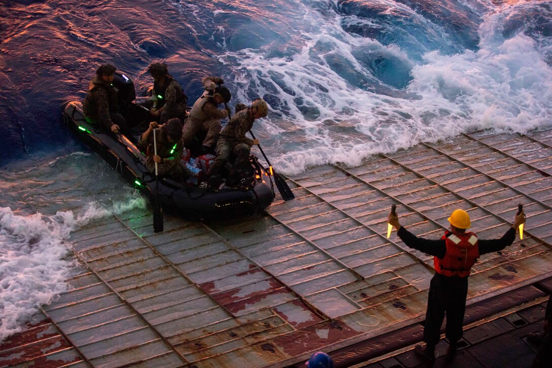A service member signals a boat as it exits a ship.