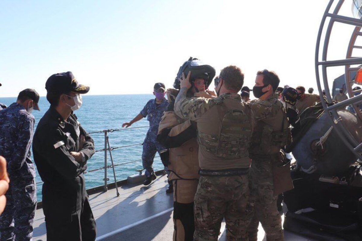Sailors help a diver into his suit.