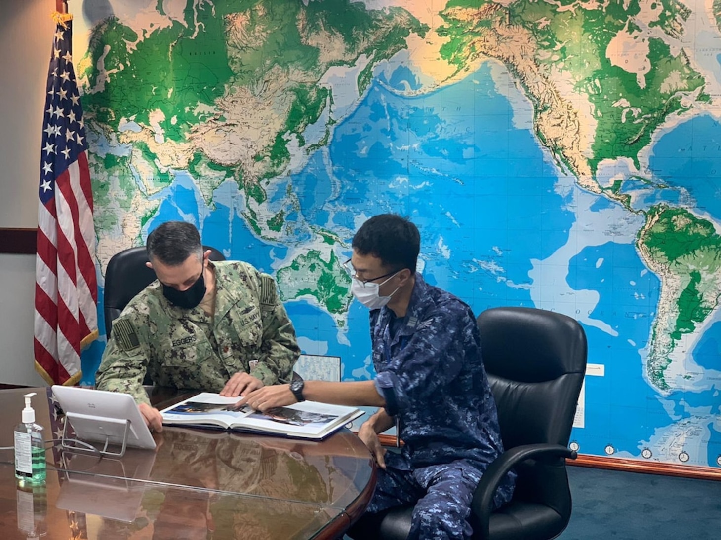 U.S. Navy Lt. Cmdr. Cory Eggers, left, replenishment officer with Commander, Logistics Group Western Pacific (COMLOG WESTPAC) and Japan Maritime Self-Defense Force Lt. Cmdr. Shuzo Homma discuss naval ships in the COMLOG WESTPAC conference room. (U.S. Navy photo by Lt. Teddy Haghverdi)