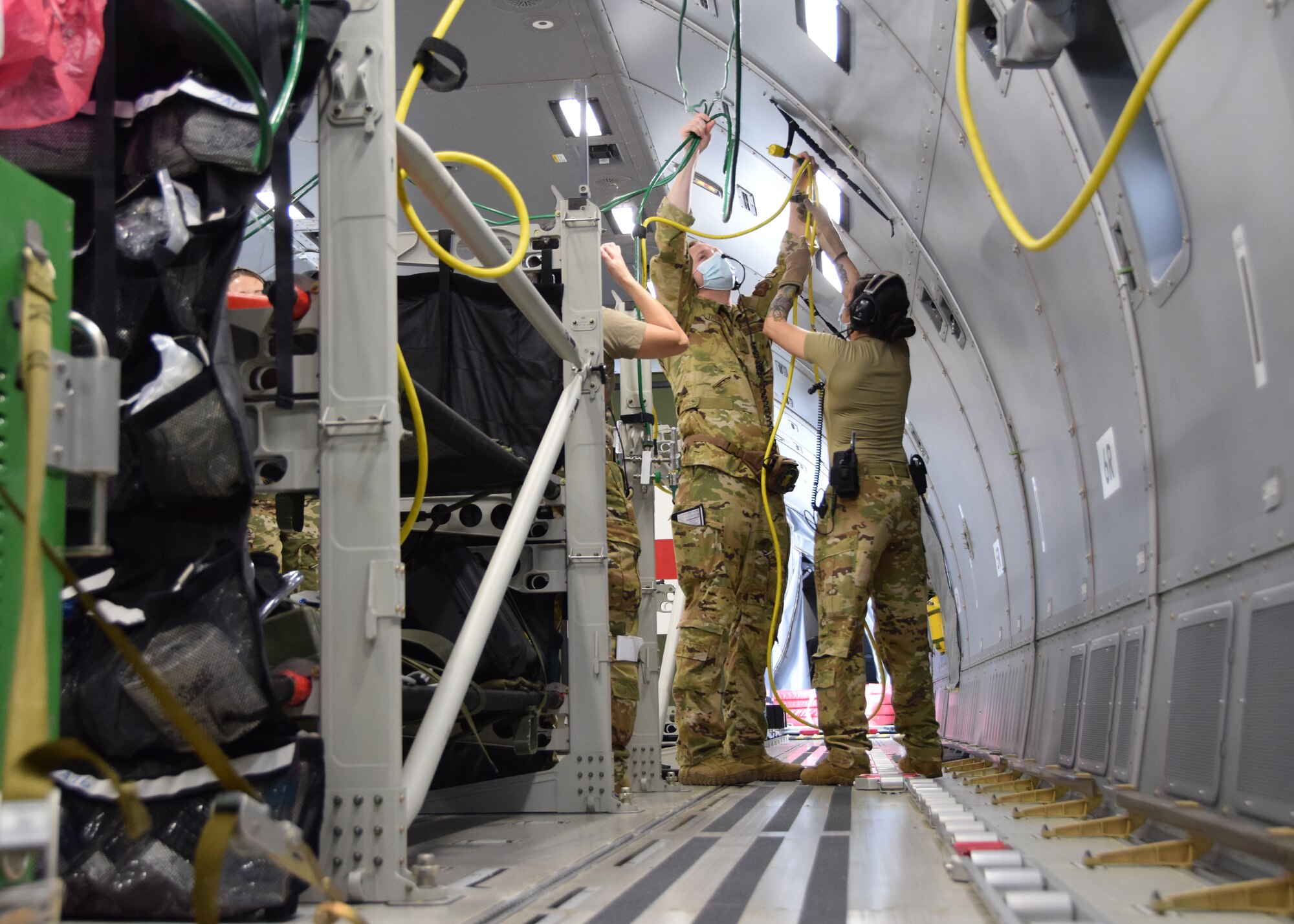 Airmen from the 433rd Aeromedical Evacuation Squadron route oxygen hoses and electrical extension cords aboard a KC-46A Pegasus March 10, 2021, at Joint Base San Antonio-Lackland, Texas. The medics were conducting initial qualification training on the new aircraft. (U.S. Air Force photo by Tech. Sgt. Iram Carmona)