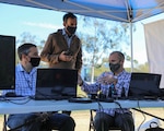 NORCO, Calif. (March 2, 2021) Communication System Engineer Ben Fellows of Naval Surface Warfare Center (NSWC) Corona Division (left) discusses operational drone capabilities with vRotors President Neil Malhotra (center) and Tom Collins of Naval Information Warfare Center Pacific during a 5G Demo Day flight test event at Norco College. The Navy's Inland Empire Tech Bridge, anchored by NSWC Corona, networked with the college to host the event, during which vRotors demonstrated technologies for the Marine Corps for a National Security Innovation Network (NSIN) 5G Starts prize challenge. (U.S. Navy photo by Nathan Fite/RELEASED)