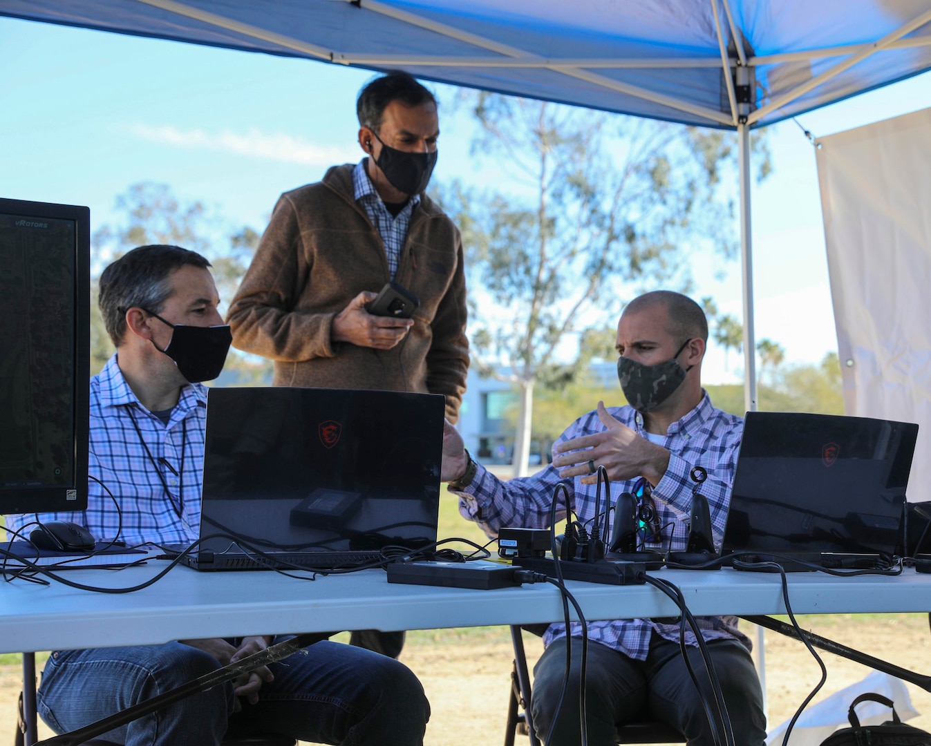 NORCO, Calif. (March 2, 2021) Communication System Engineer Ben Fellows of Naval Surface Warfare Center (NSWC) Corona Division (left) discusses operational drone capabilities with vRotors President Neil Malhotra (center) and Tom Collins of Naval Information Warfare Center Pacific during a 5G Demo Day flight test event at Norco College. The Navy's Inland Empire Tech Bridge, anchored by NSWC Corona, networked with the college to host the event, during which vRotors demonstrated technologies for the Marine Corps for a National Security Innovation Network (NSIN) 5G Starts prize challenge. (U.S. Navy photo by Nathan Fite/RELEASED)