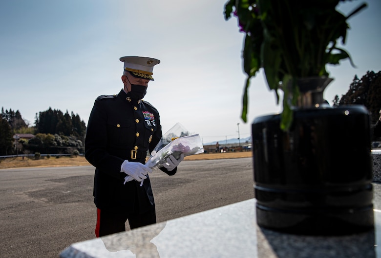U.S. Marine Corps Brig. Gen. William Bowers, Marine Corps Installations Pacific commanding general, places flowers on a memorial on Oshima Island, Japan, March 11, 2021. The memorial recognizes the 33 people from Oshima Island who lost their lives in the 2011 Great East Japan earthquake and tsunami. (U.S. Marine Corps photo by Lance Cpl. Alex Fairchild)