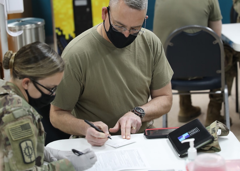 Army Reserve Command Sgt. Maj. Keith Gwin, deployed to Camp Arifjan, Kuwait, as the senior enlisted advisor to the deputy commanding general of 1st Theater Sustainment Command, reviews his paperwork before receiving the one-dose Janssen Biotech COVID-19 vaccine at the camp's March 13, 2021 rollout of Operation Med Spear. Gwin said, "Soldiers really need to get onboard to take the vaccine, so we can get back to more normalcy." (U.S. Army photo by Staff Sgt. Neil W. McCabe)