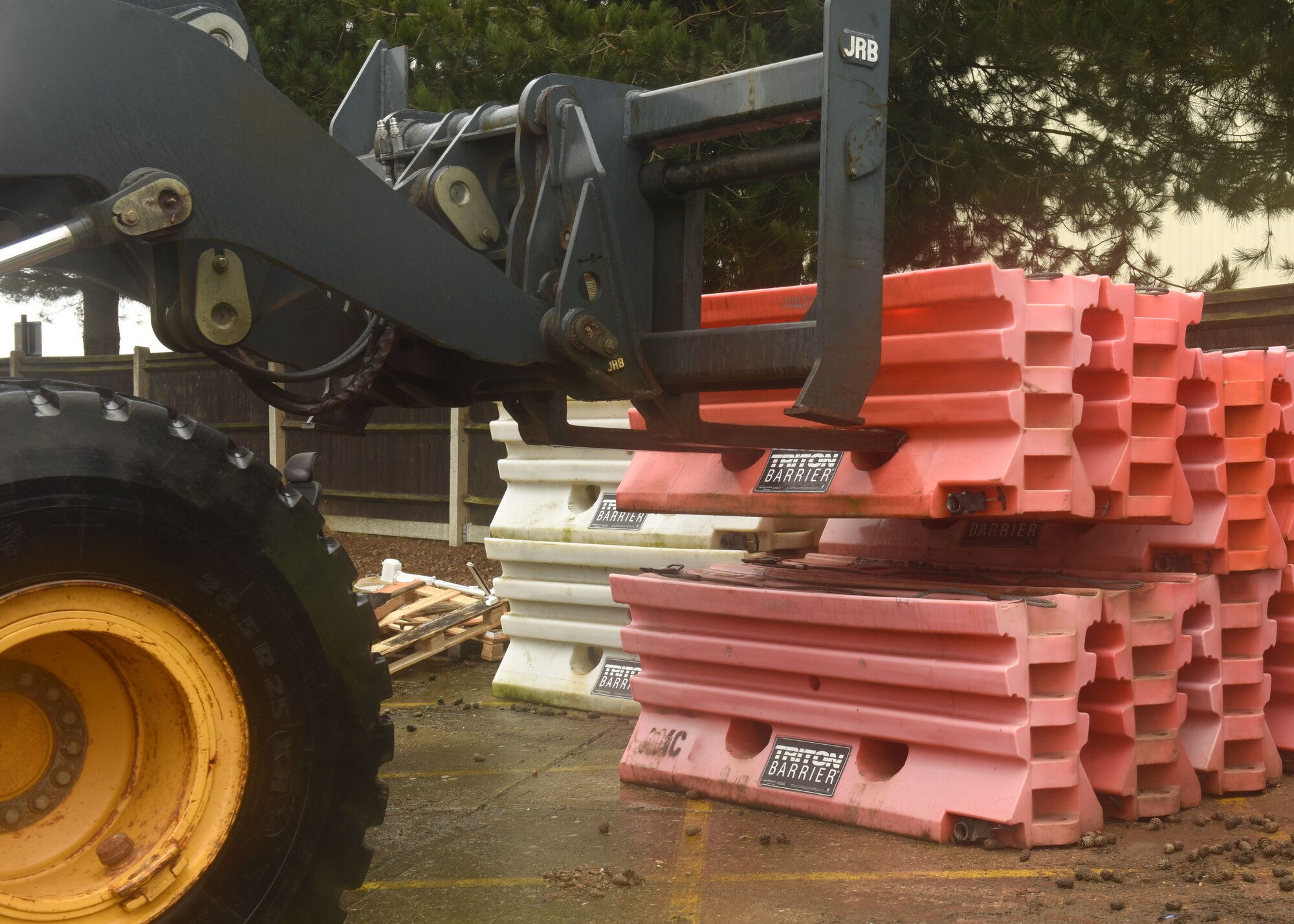 U.S. Air Force Senior Airman Tyler Miller, 100th Civil Engineer Squadron, drives a loader to pick up water barriers before positioning them in place outside a facility during an exercise at Royal Air Force Mildenhall, England, March 17, 2021. The barriers were placed next to concrete Jersey barriers on sidewalks to stop possibly entry by small vehicles such as motorcycles as part of a Barrier Defense Plan initiative. (U.S. Air Force photo by Karen Abeyasekere)