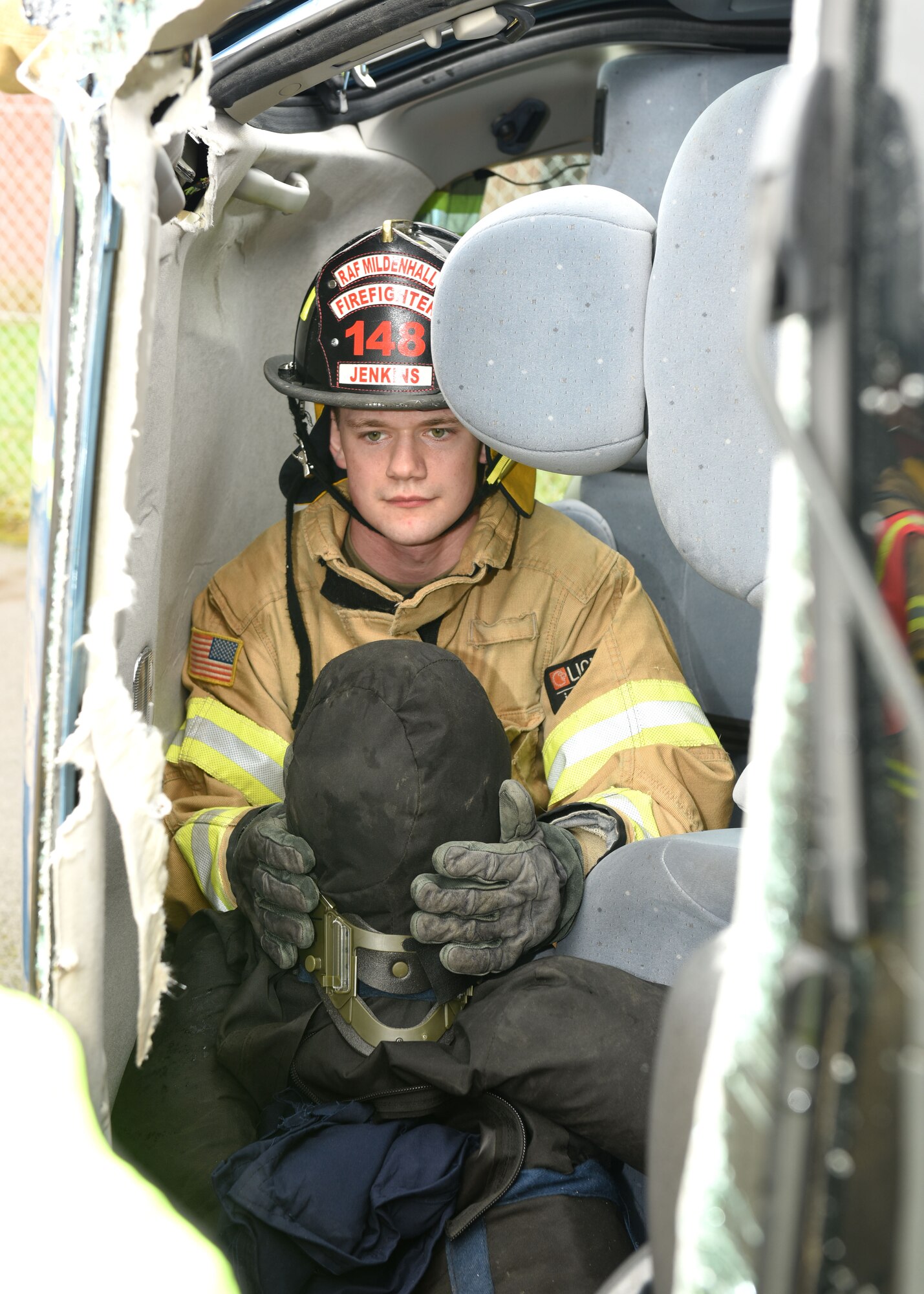 U.S. Air Force Senior Airman Justin Jenkins, 100th Civil Engineer Squadron Fire Department firefighter, holds the head of a simulated trapped casualty inside an overturned car during a simulated car crash scenario as part of an exercise at Royal Air Force Mildenhall, England, March 16, 2021. The exercise was made up of a variety of scenarios to test the base’s emergency response and base defense for potential threats. (U.S. Air Force photo by Karen Abeyasekere)