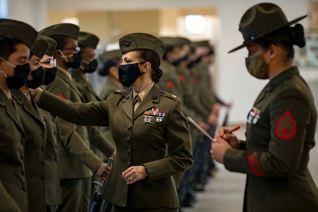A Marine inspects fellow Marines who are standing in formation.