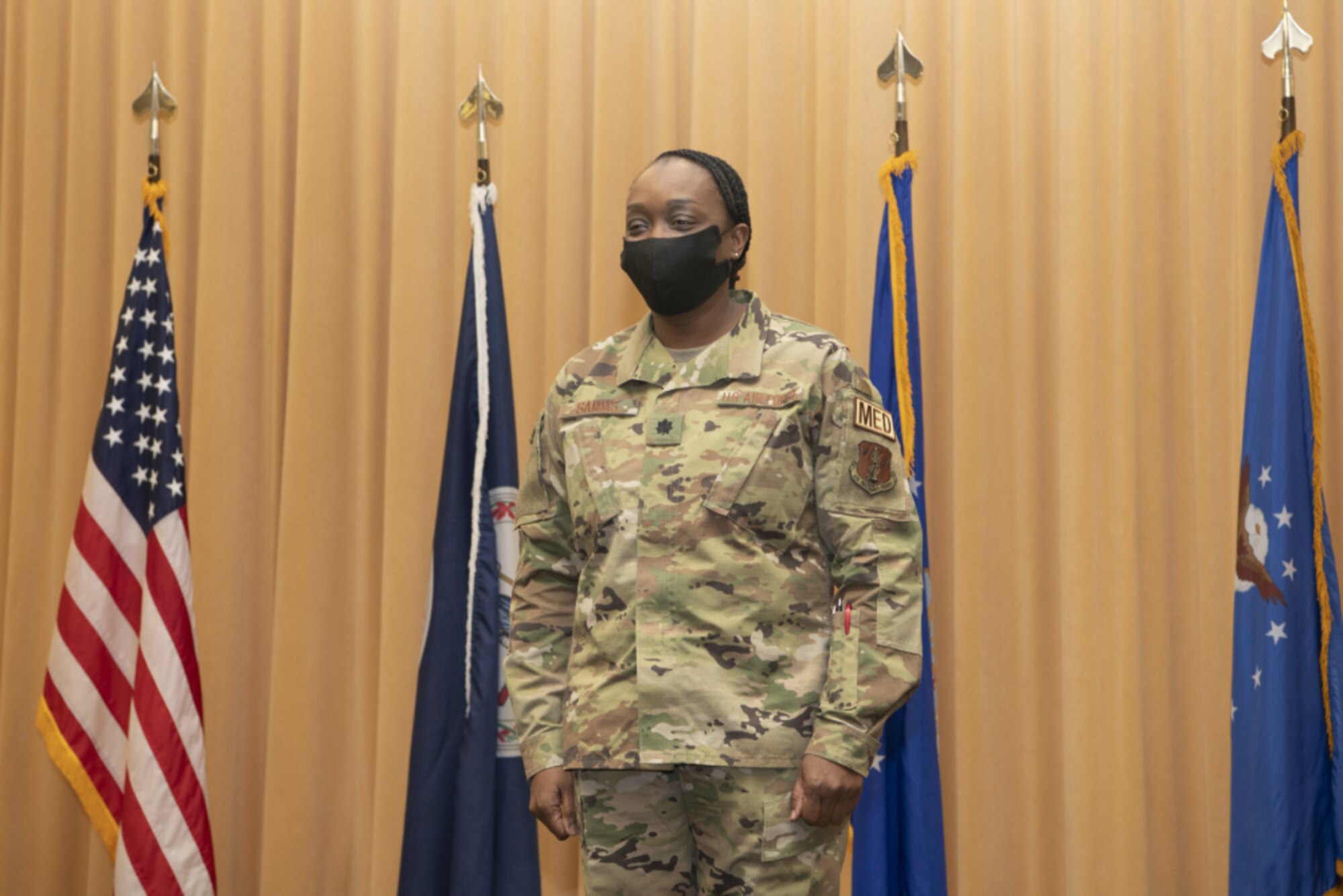 An Airman stands in front of flags