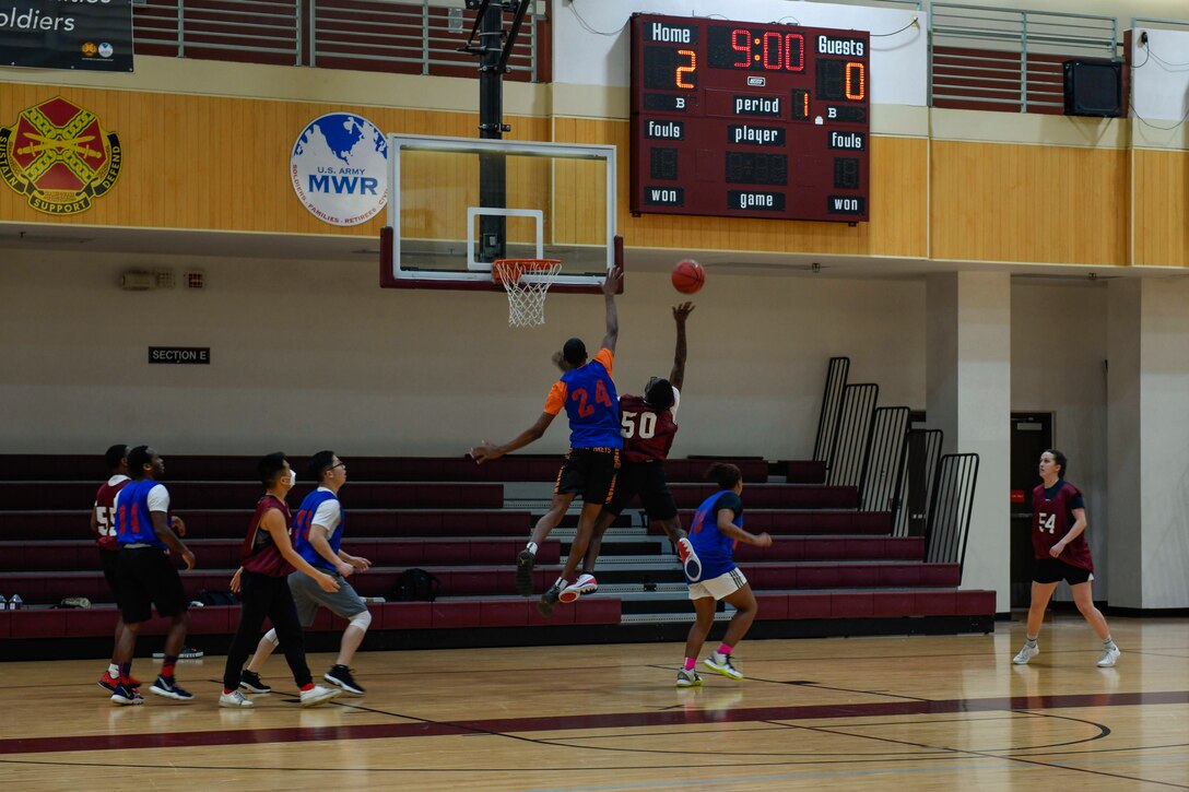 A soldier blocks another soldier’s shot during a basketball game.